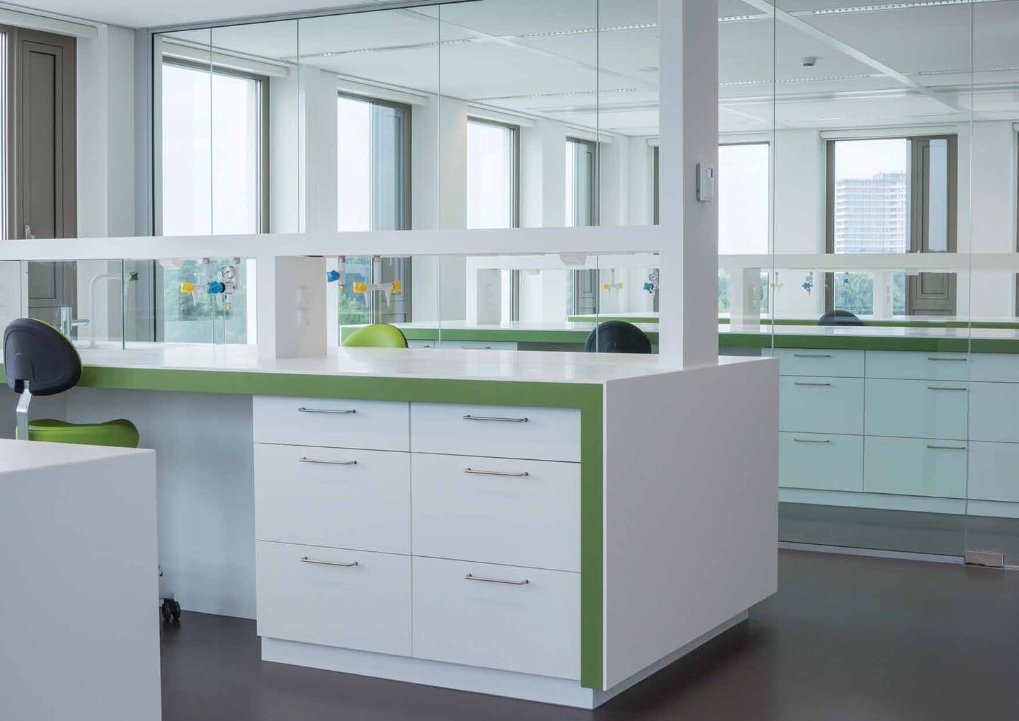 FrieslandCampina laboratoriuminterieur Wageningen — witte werkbanken met groene accenten en glazen wanden